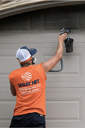 Spray-Net employee spray painting a garage door