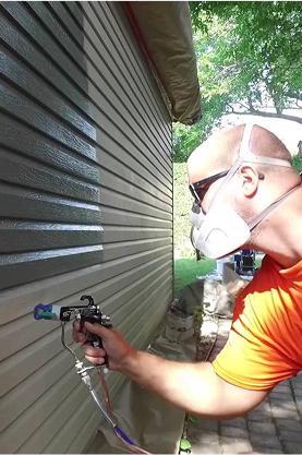 Spray-Net employee painting aluminum siding of a shed