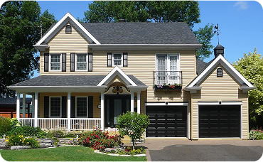 Tan house with white trim and two black garage doors