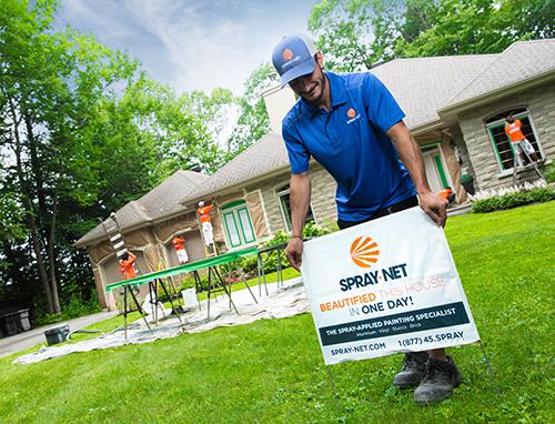 Spray-Net employee placing signage outside home