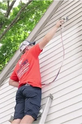 Spray-Net employee painting the side of a house
